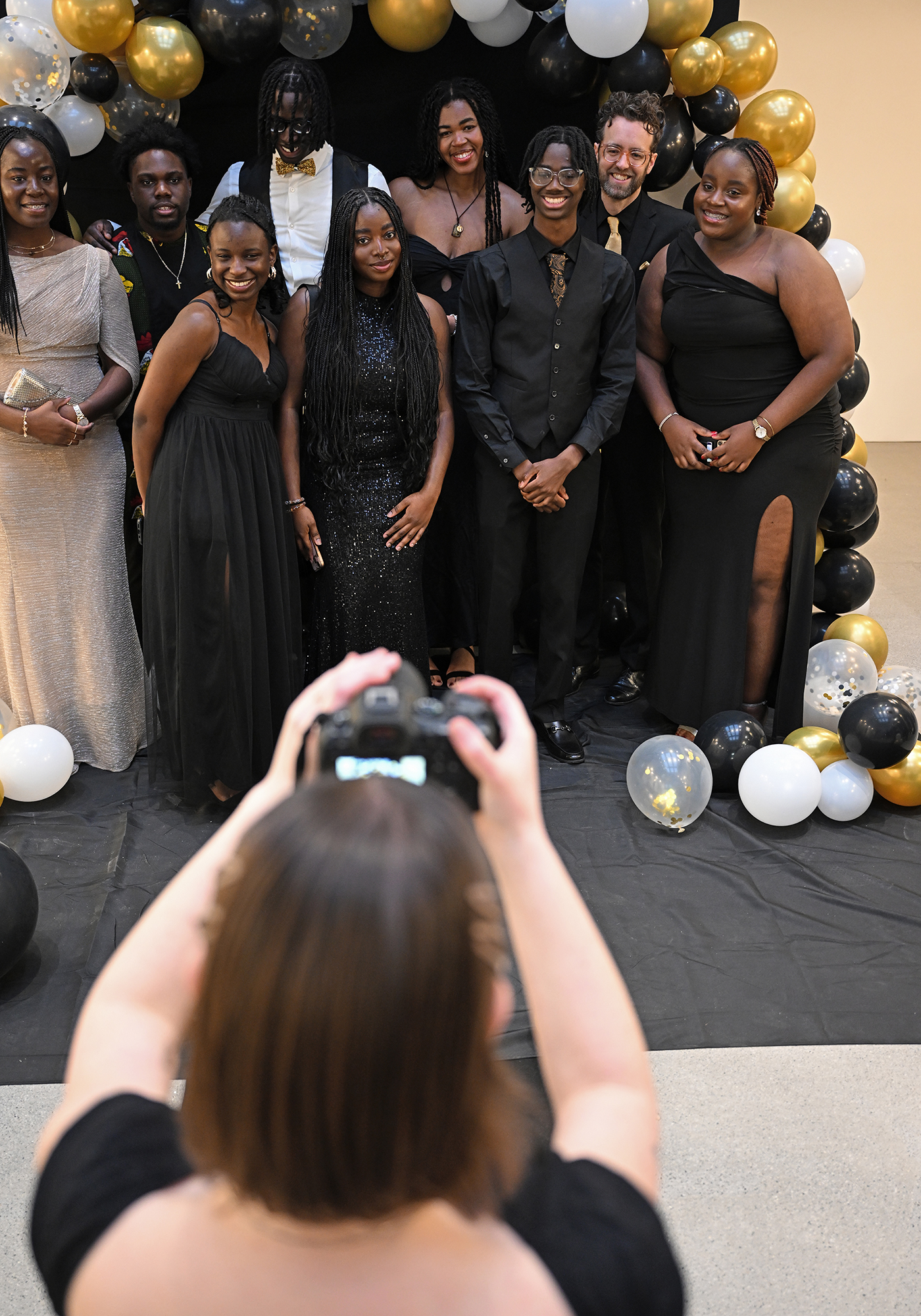 photographer takes photo of group of students in formal attire