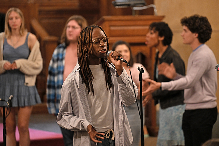 A solo singer performs out in front of an a cappella group