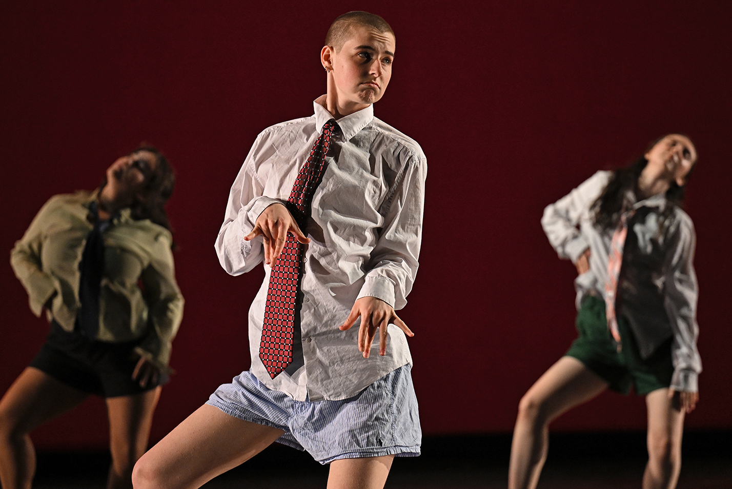 A dancer in white button-down shirt and tie performs on stage.