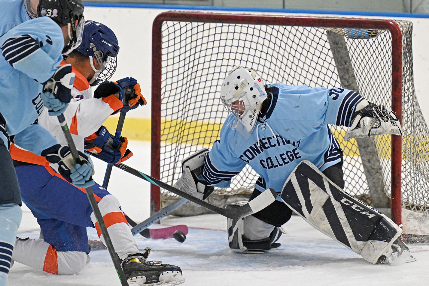 An ice hockey goalie keeps his eye on the puck bouncing in front of the net.