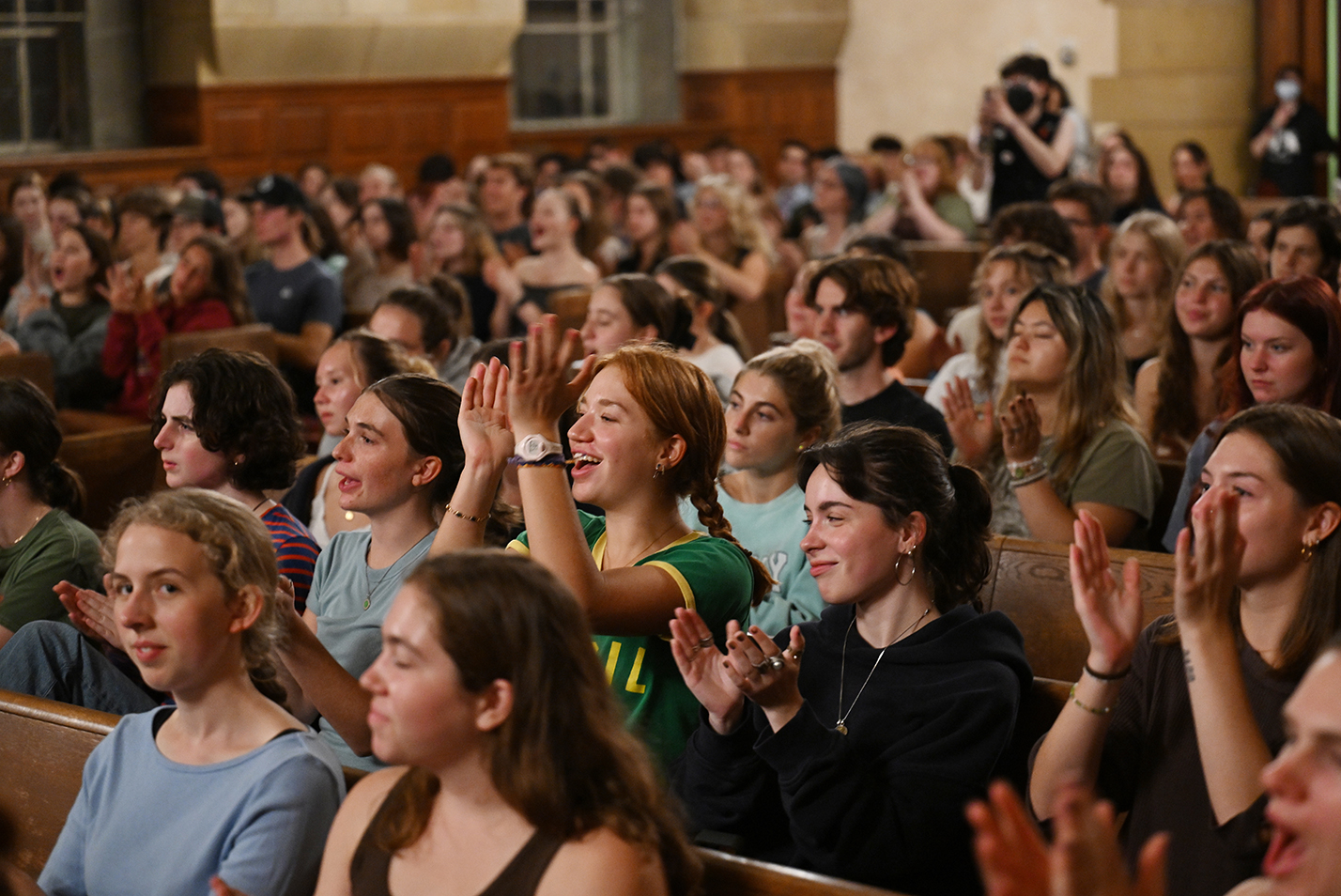 A crowd of students clap and cheer at an a cappella performance