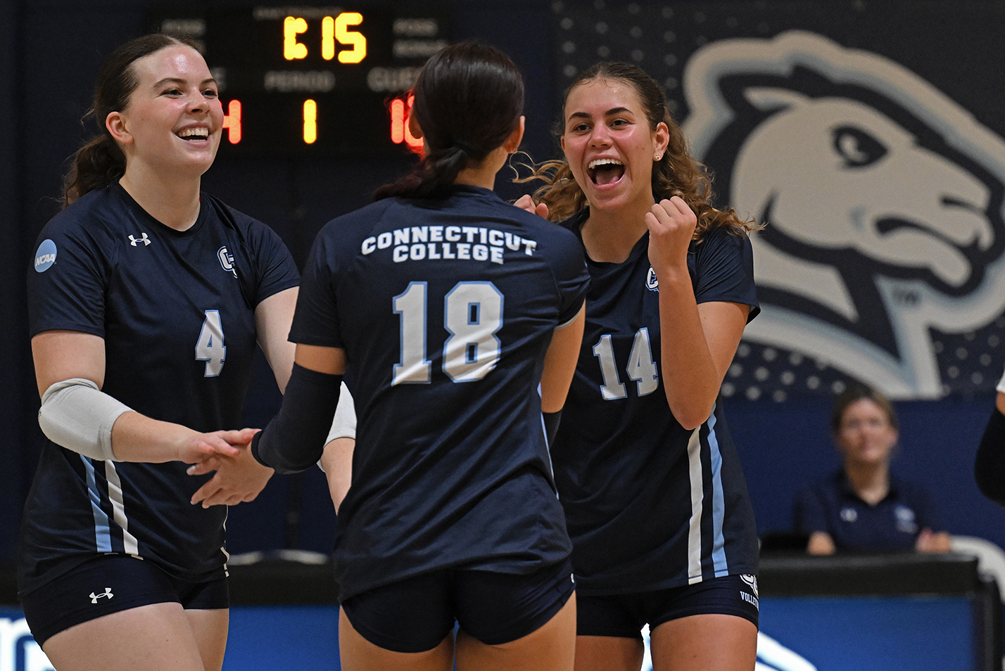 three volleyball players celebrate a point